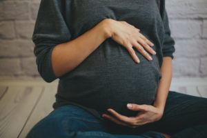 Closeup of pregnant woman cradling stomach