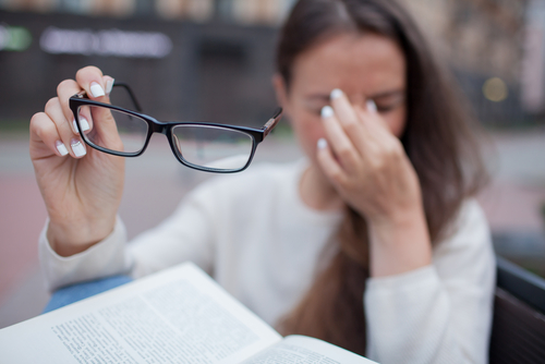 Woman rubbing eyes due to Dry Eye Sundrome