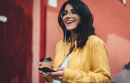Smiling Young Woman Using Phone and Drinking Coffee