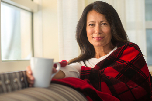 Woman with cup of coffee wearing blanket