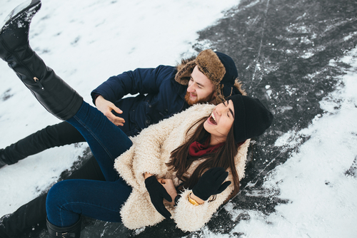 man and woman smiling while laying in the snow