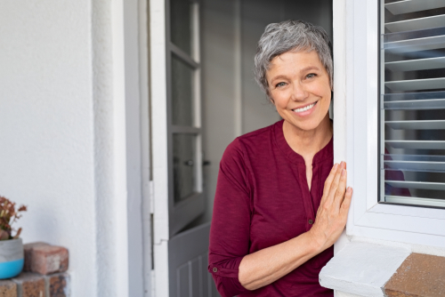 older woman smiling while standing in doorway